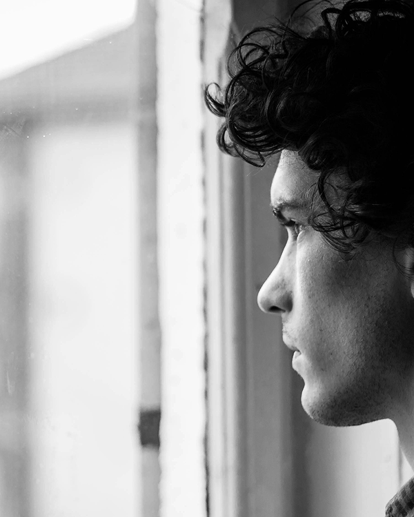 Black and white photo of man looking out window